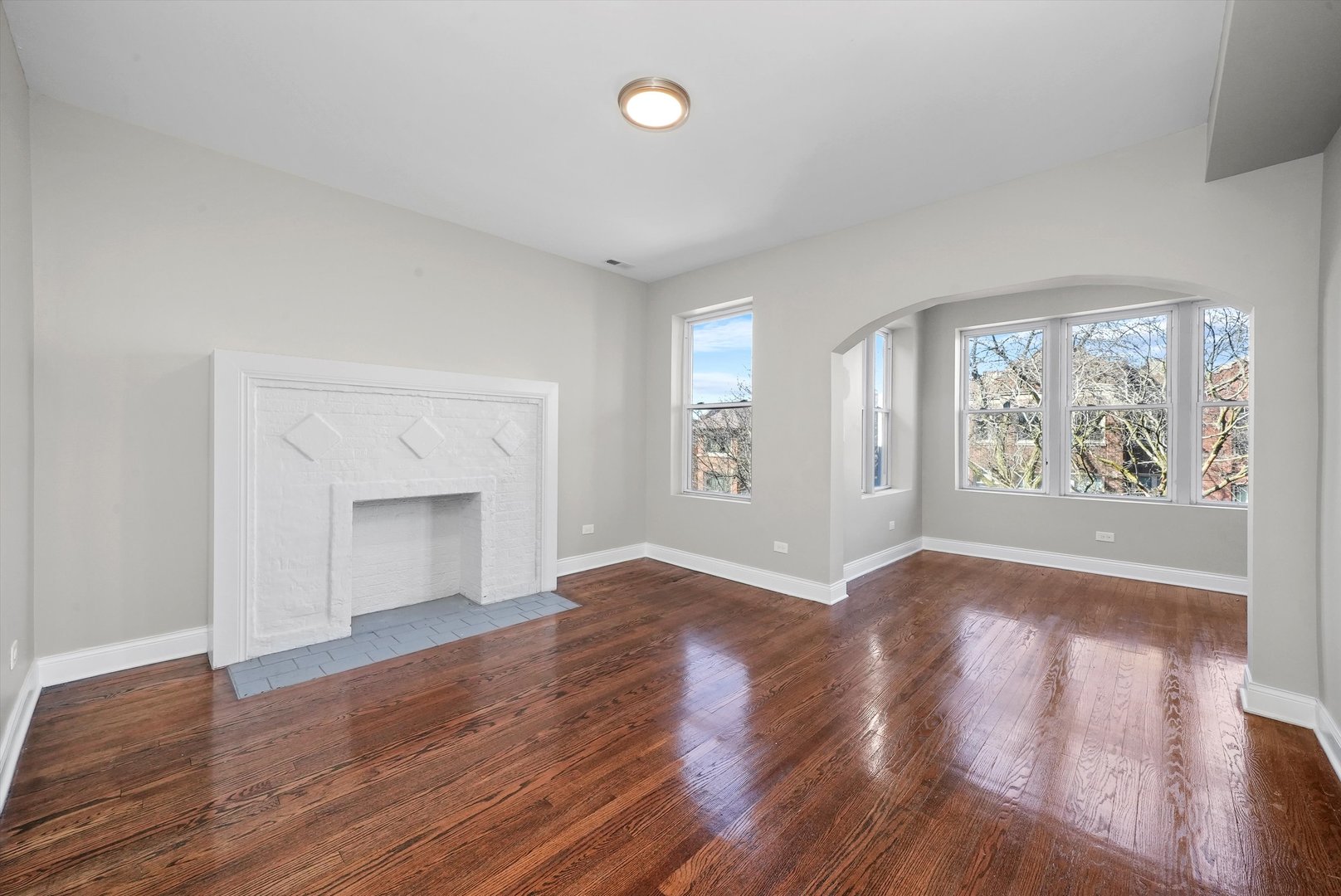 6833 South Merrill Avenue, Unit 1 Chicago, IL 60649 - Photo 4 of 10 an empty room with wooden floor and windows