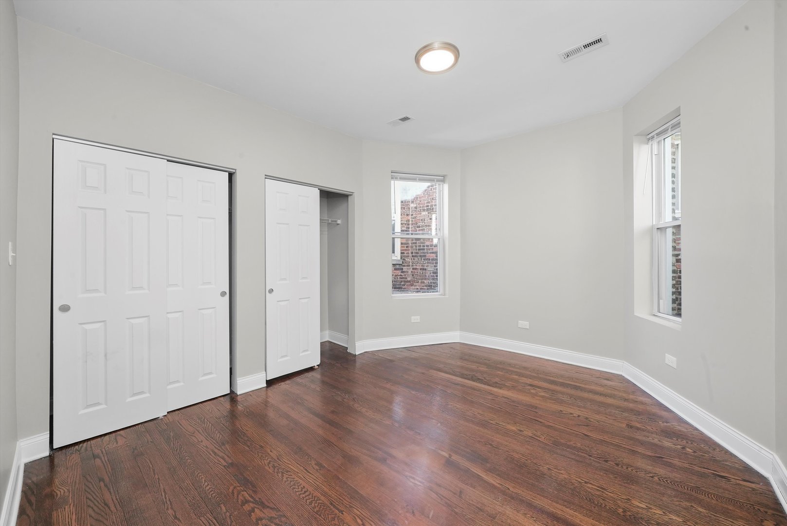 6833 South Merrill Avenue, Unit 1 Chicago, IL 60649 - Photo 8 of 10 an empty room with wooden floor and windows