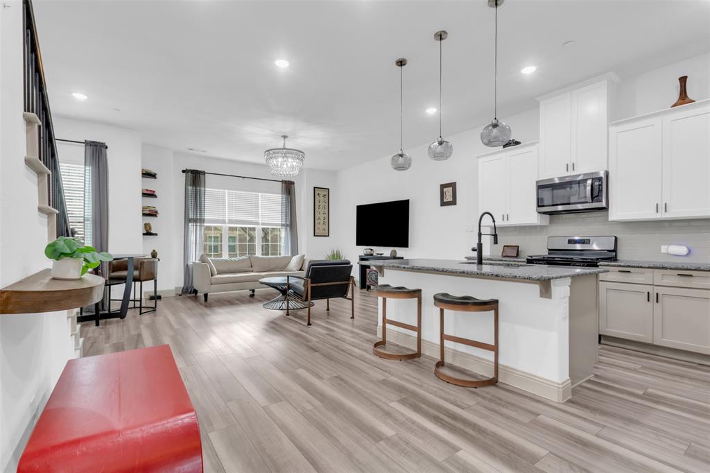 4153 Shavano Drive Frisco, TX 75034 - Photo 11 of 35 a living room with stainless steel appliances kitchen island granite countertop a stove a sink a dining table and chairs with wooden floor