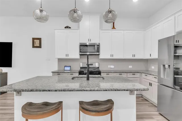a kitchen with granite countertop cabinets a sink and stainless steel appliances