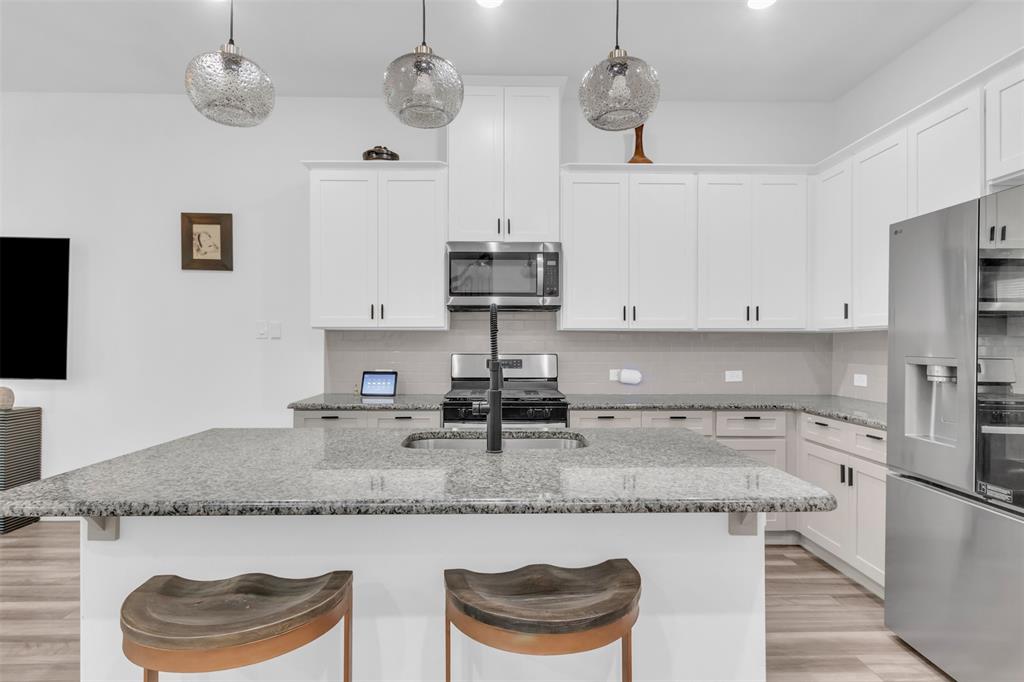 4153 Shavano Drive Frisco, TX 75034 - Photo 12 of 35 a kitchen with granite countertop cabinets a sink and stainless steel appliances