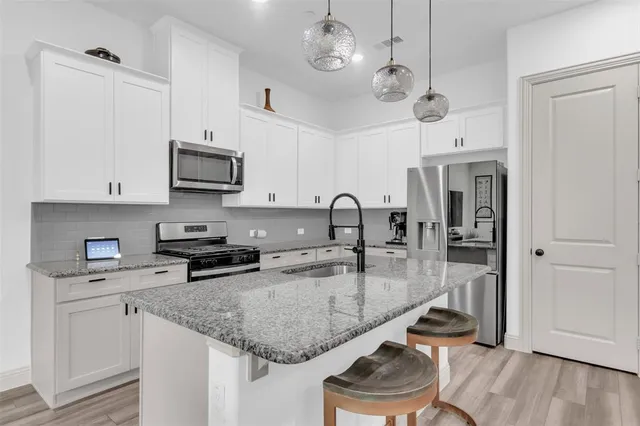 a kitchen with stainless steel appliances granite countertop a sink a stove and a wooden floors