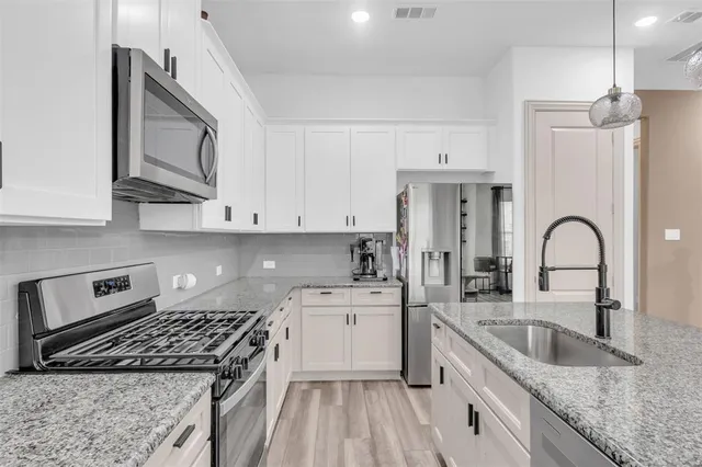 a kitchen with stainless steel appliances granite countertop a sink stove refrigerator and cabinets