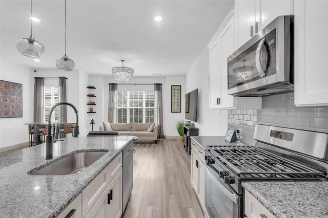 a kitchen with stainless steel appliances granite countertop a sink stove and cabinets