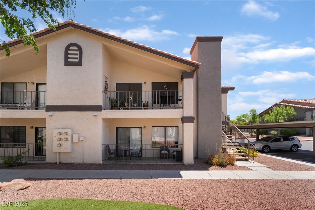 1575 West Warm Springs Road, Unit 2822 Henderson, NV 89014 - Photo 4 of 37 Back of house with stucco siding, stairs, covered parking, and a tiled roof