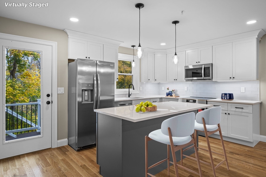 9 Acton Road, Unit 10 Chelmsford, MA 01824 - Photo 3 of 15 a kitchen with stainless steel appliances granite countertop a refrigerator a stove a sink a dining table and chairs with wooden floor