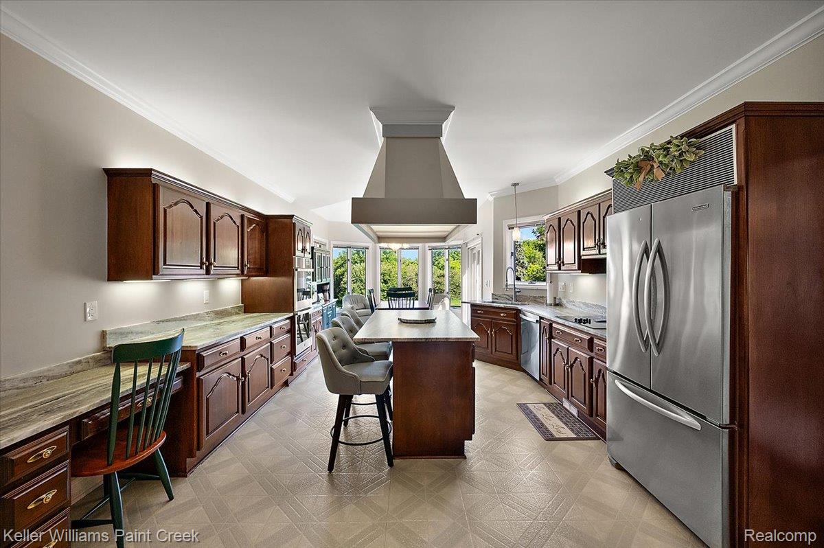69069 Campground Road Romeo, MI 48065 - Photo 31 of 78 Spacious kitchen featuring extensive dark wood cabinetry, light-toned countertops, tile flooring, stainless steel appliances, and a central island with seating