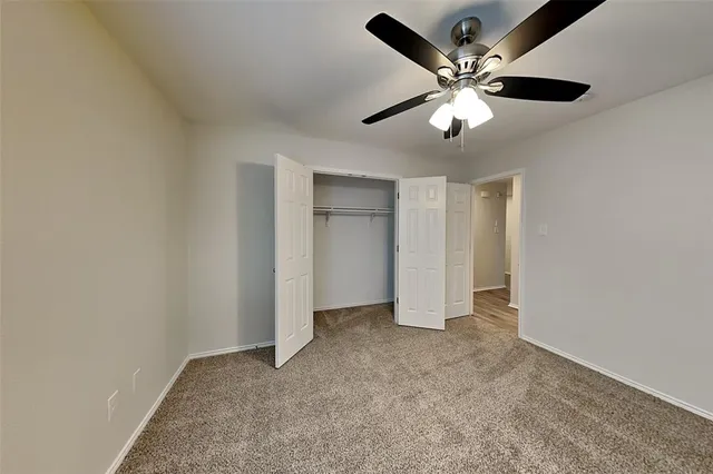 an empty room with closet and a ceiling fan