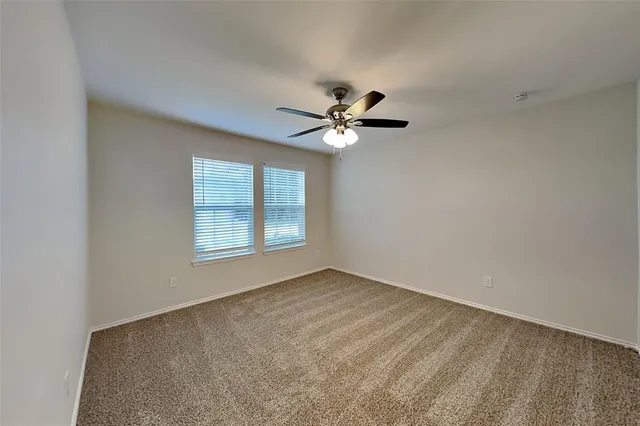 an empty room with windows and ceiling fan