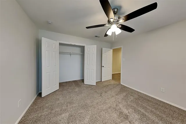 an empty room with closet and a ceiling fan