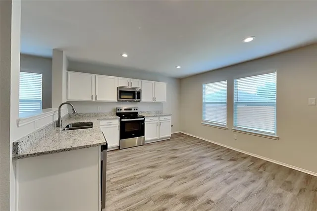 a kitchen with granite countertop stainless steel appliances a sink stove and cabinets