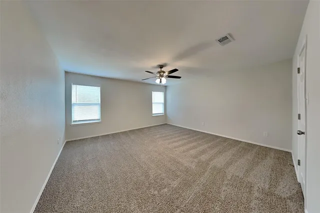 an empty room with a chandelier fan and windows