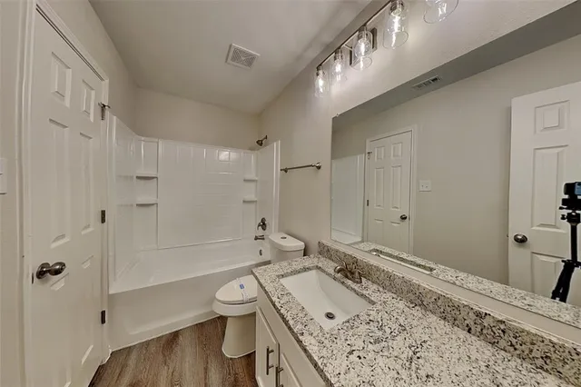 a bathroom with a granite countertop sink a toilet and shower