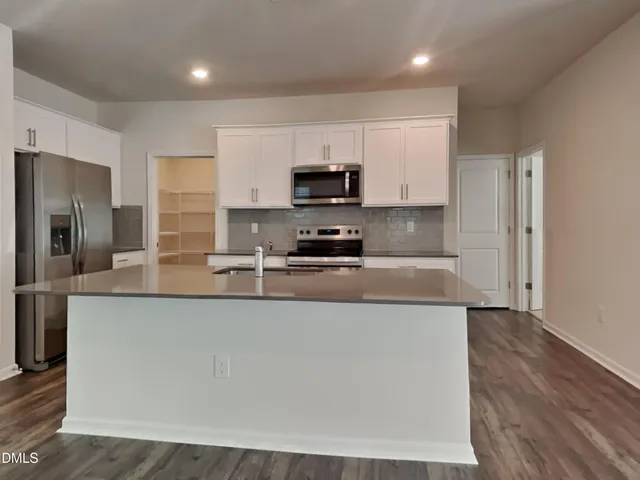 a large kitchen with stainless steel appliances granite countertop a stove a sink and a refrigerator