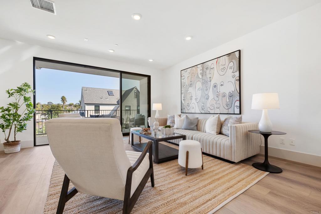 310-326 Chinquapin Avenue Carlsbad, CA 92008 - Photo 10 of 33 a living room with couches a coffee table and lamp next to a window with wooden floor