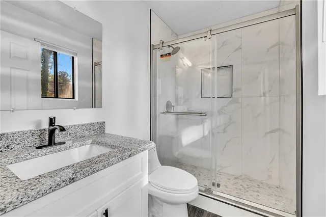 a bathroom with a granite countertop sink toilet and shower