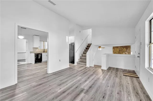 a view of a big room with wooden floor and kitchen