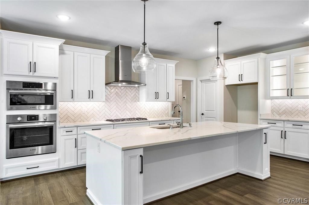 a kitchen with stainless steel appliances kitchen island a stove a sink a refrigerator a center island a stove and white cabinets with wooden floor