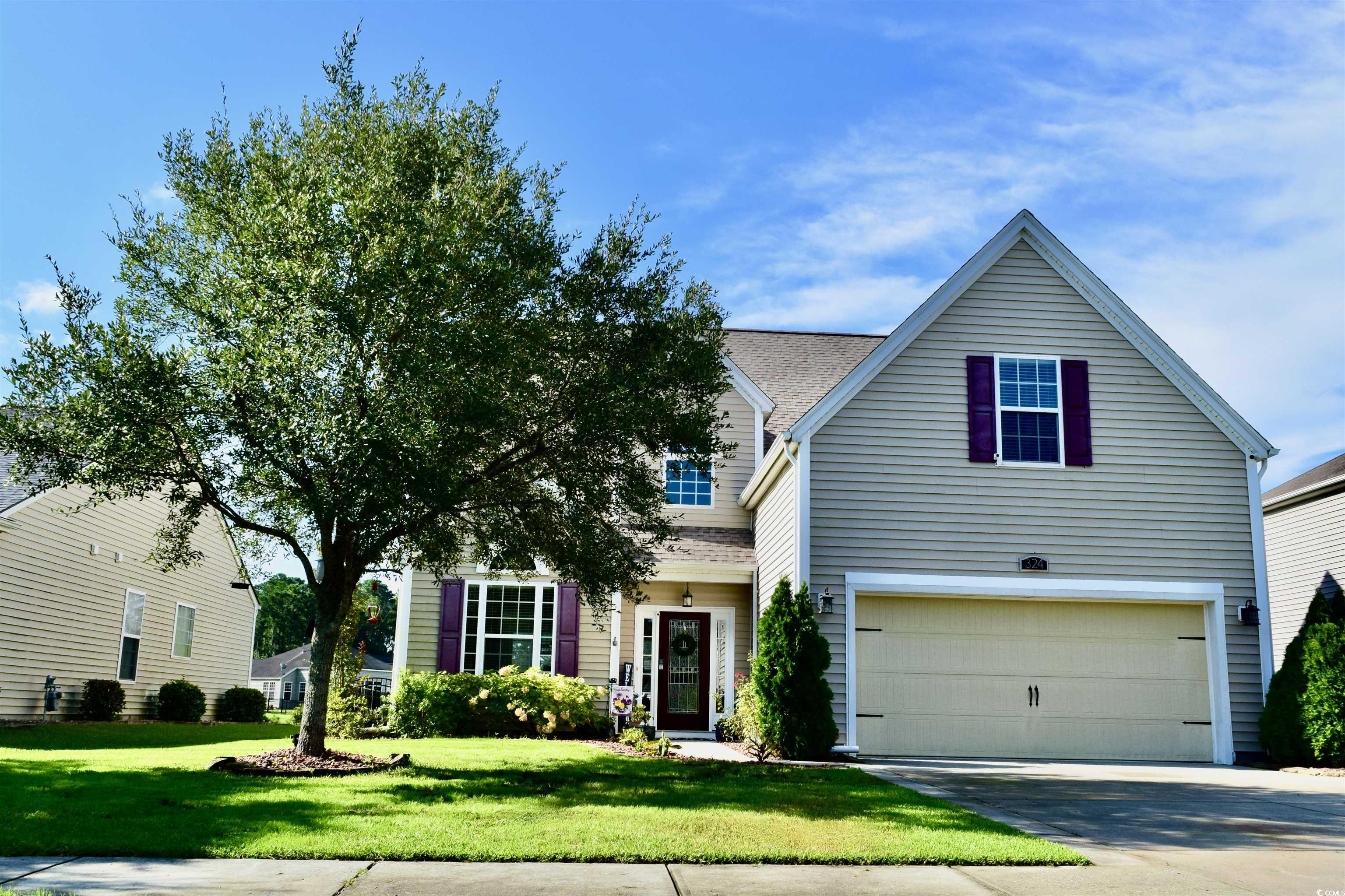 Traditional home featuring a garage, a front lawn, driveway, and roof with shingles