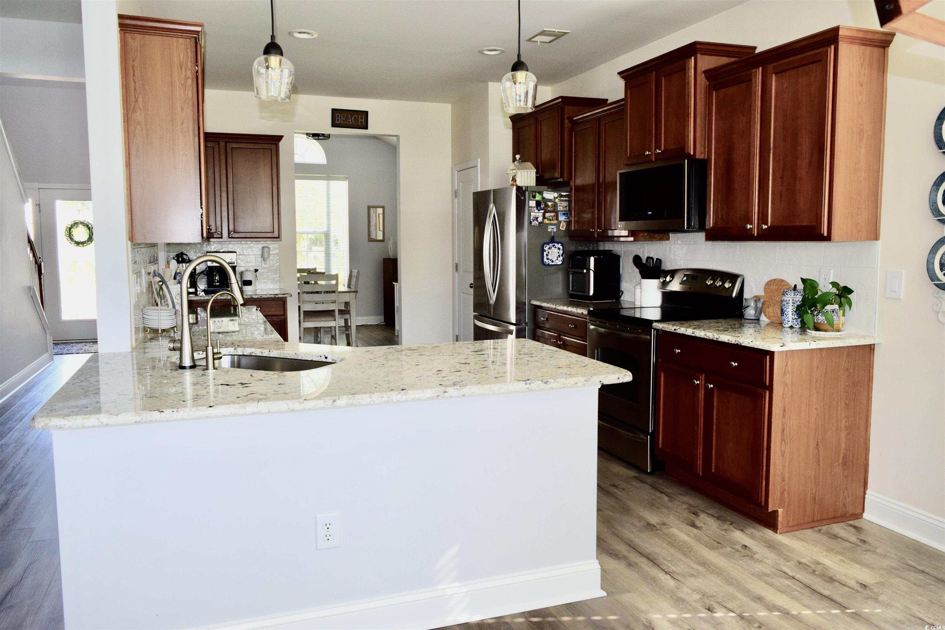 324 Oak Haven Drive Murrells Inlet, SC 29576 - Photo 11 of 38 Kitchen with a peninsula, tasteful backsplash, appliances with stainless steel finishes, light wood finished floors, and light stone countertops