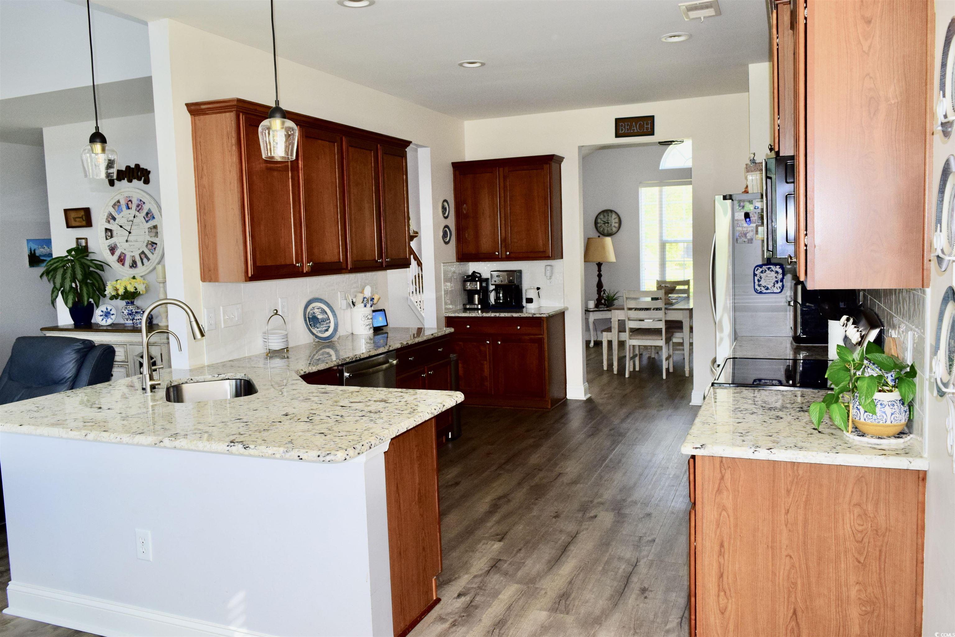 324 Oak Haven Drive Murrells Inlet, SC 29576 - Photo 13 of 38 Kitchen with a peninsula, light stone counters, light wood-style floors, hanging light fixtures, and tasteful backsplash