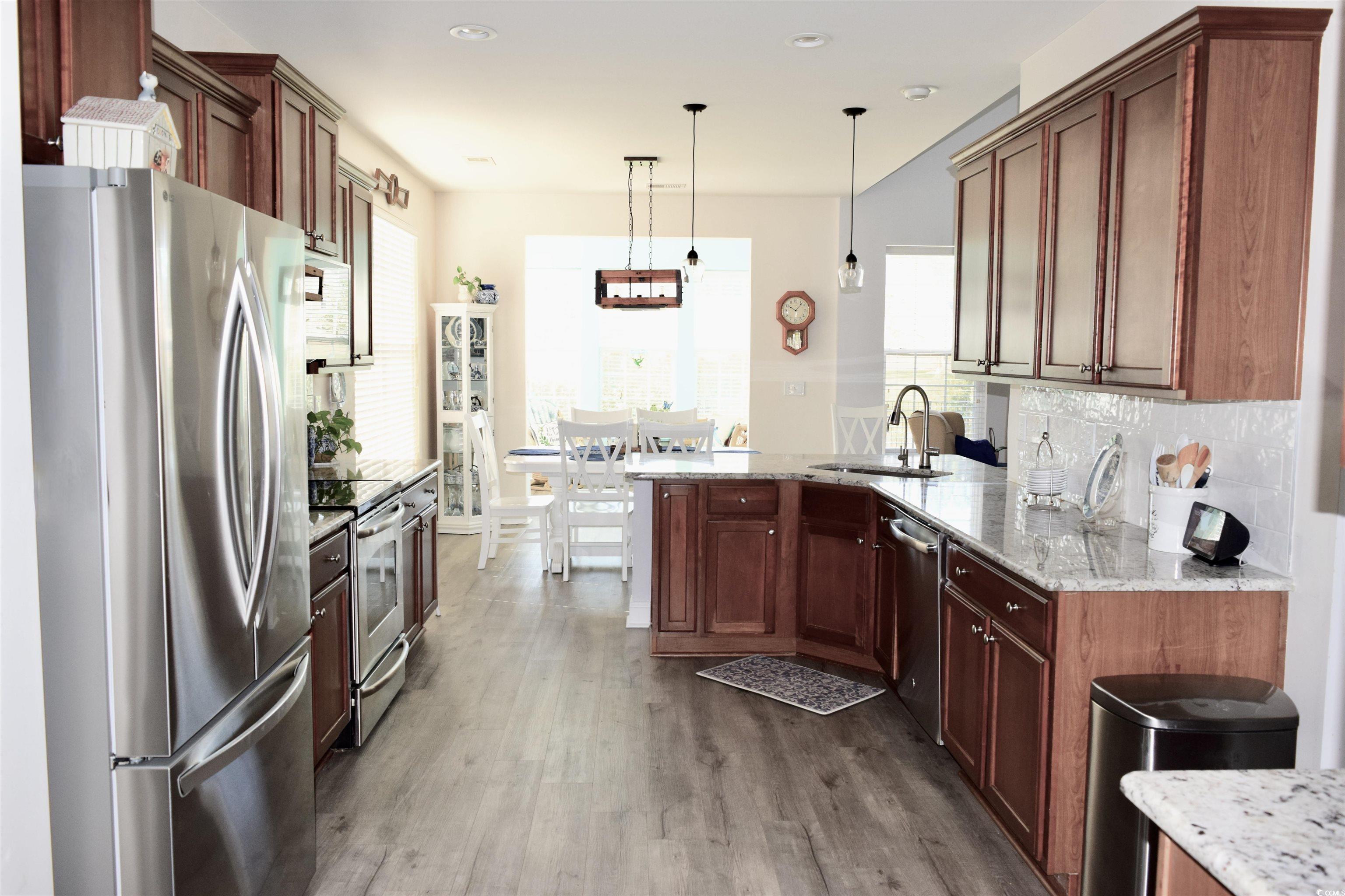 324 Oak Haven Drive Murrells Inlet, SC 29576 - Photo 10 of 38 Kitchen featuring appliances with stainless steel finishes, a peninsula, light stone countertops, dark wood finished floors, and pendant lighting