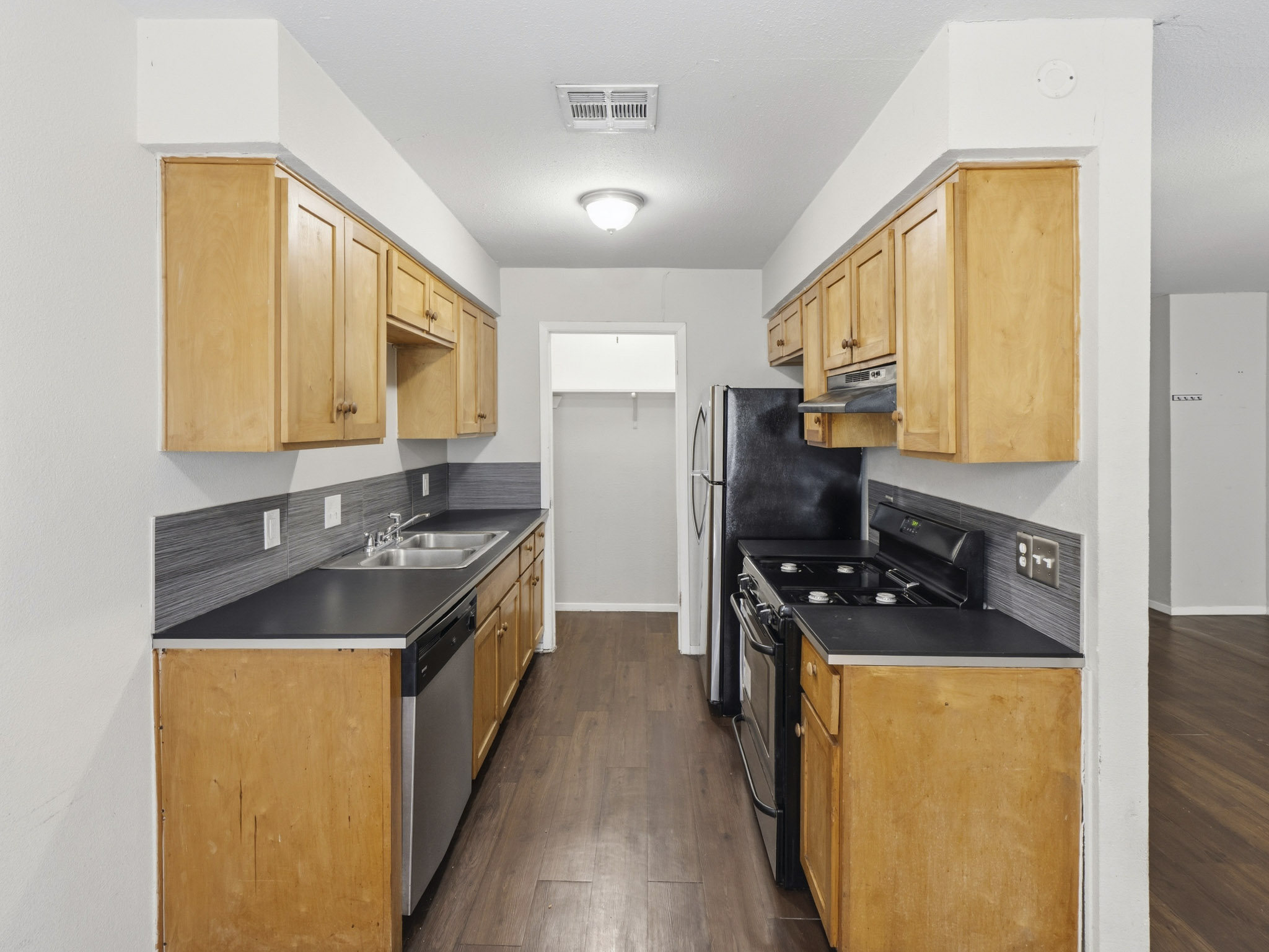 2401 Burleson Road Austin, TX 78741 - Photo 17 of 25 Functional galley kitchen features ample wooden cabinetry and durable dark countertops.
