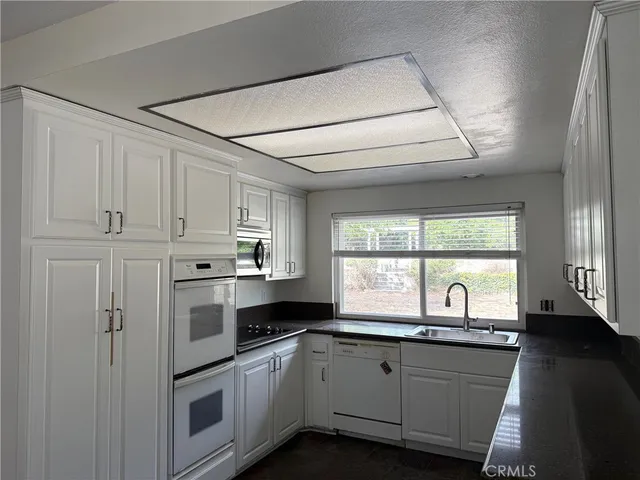 a kitchen with granite countertop white cabinets and white appliances