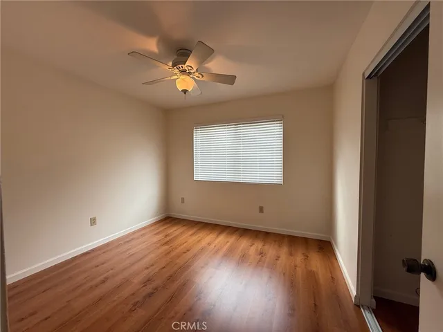 an empty room with wooden floor chandelier fan and windows