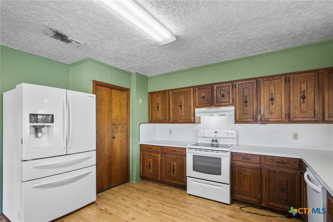 1720 Lower Mission Valley Road Victoria, TX 77905 - Photo 8 of 30 a kitchen with a white stove refrigerator and cabinets