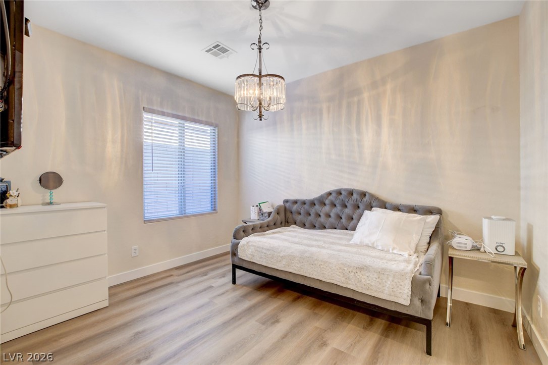 2649 Rue Marquette Avenue Henderson, NV 89044 - Photo 36 of 55 This cozy bedroom features durable vinyl plank flooring and a stylish chandelier, creating a comfortable and inviting atmosphere.
