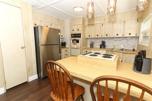 a kitchen with stainless steel appliances a refrigerator a stove a sink and white cabinets with wooden floor