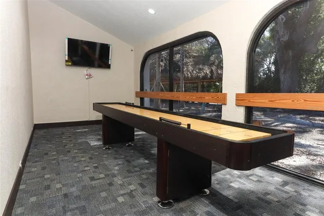 a living room with table a flat screen tv and a large window