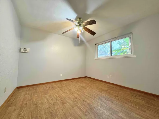 a view of an empty room with window and wooden floor