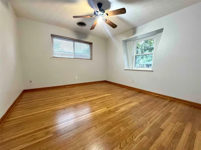 a view of an empty room with a window and wooden floor