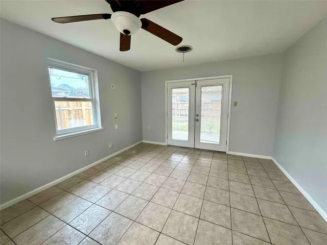 a view of an empty room with window and chandelier fan