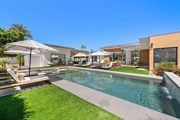 a view of an house with swimming pool and chairs