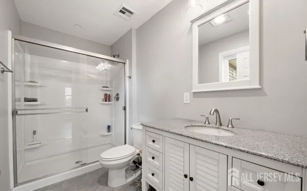 a bathroom with a granite countertop sink toilet and shower