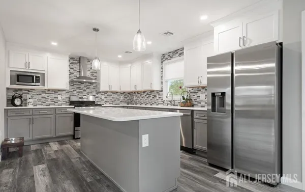 a kitchen with kitchen island granite countertop a refrigerator a sink a stove and cabinets