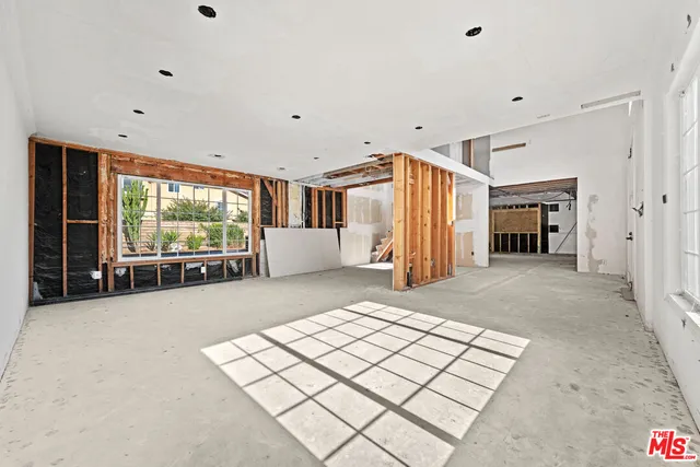an empty room with floor to ceiling window and refrigerator