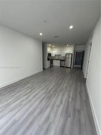 a view of a room with wooden floor stairs and a kitchen space
