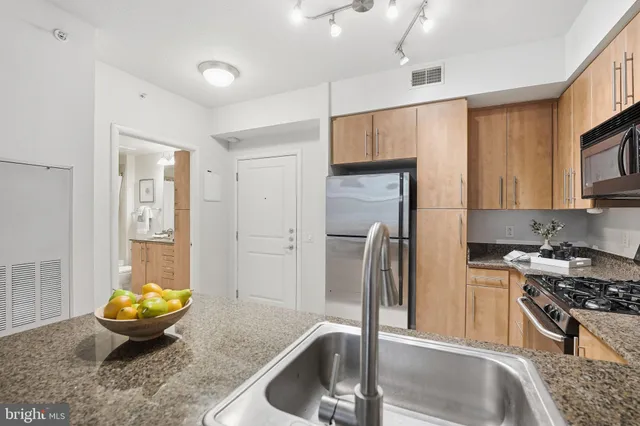 a kitchen with stainless steel appliances granite countertop a sink and a refrigerator