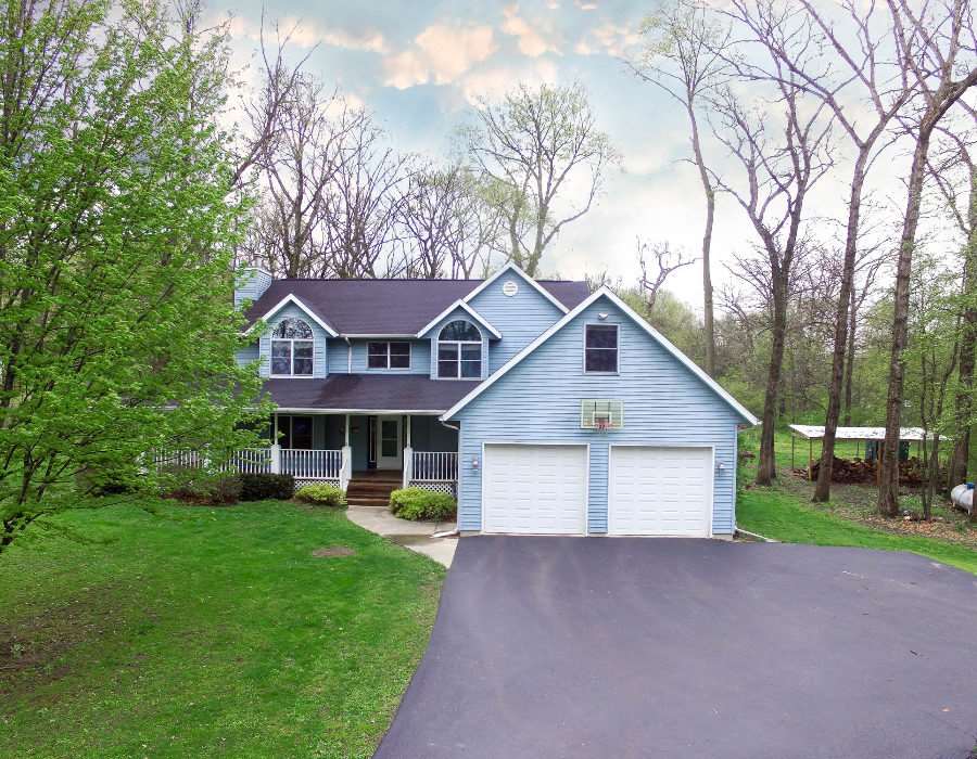 a view of a house with a yard and large trees