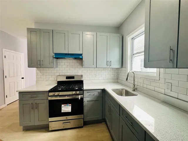 a kitchen with granite countertop a sink a stove and cabinets
