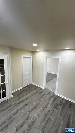 a view of an empty room with wooden floor and closet