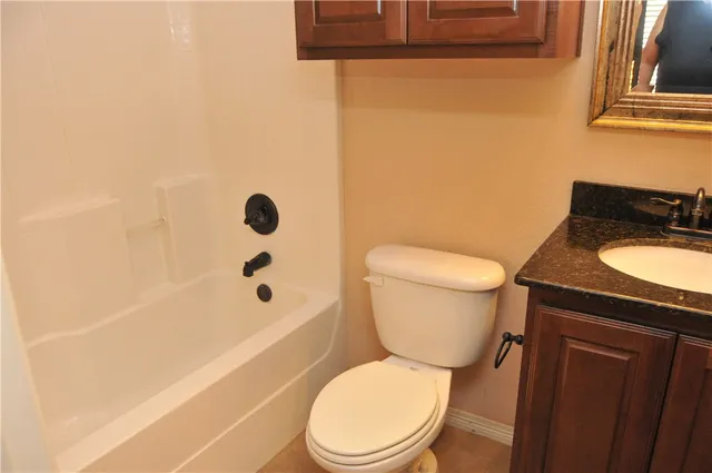 a bathroom with a granite countertop toilet a sink and a bathtub