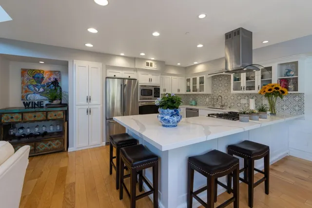 a kitchen with stainless steel appliances a dining table chairs and refrigerator