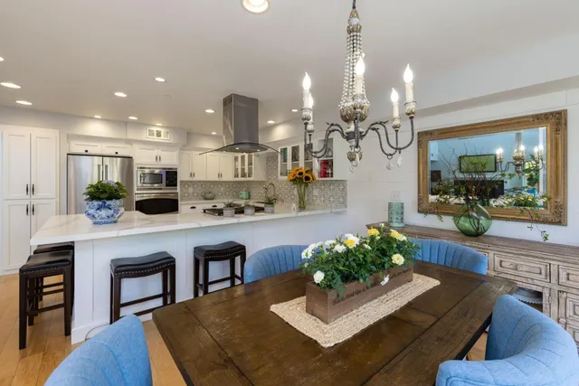 a kitchen with stainless steel appliances granite countertop sink refrigerator dining table and chairs