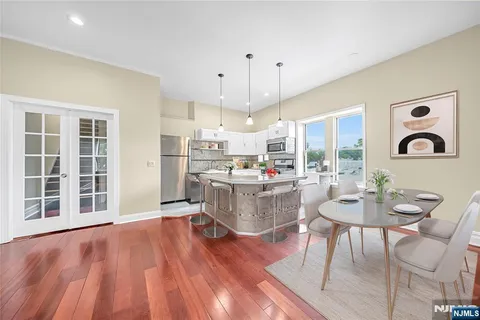 a large kitchen with granite countertop a stove a sink and white cabinets with wooden floor
