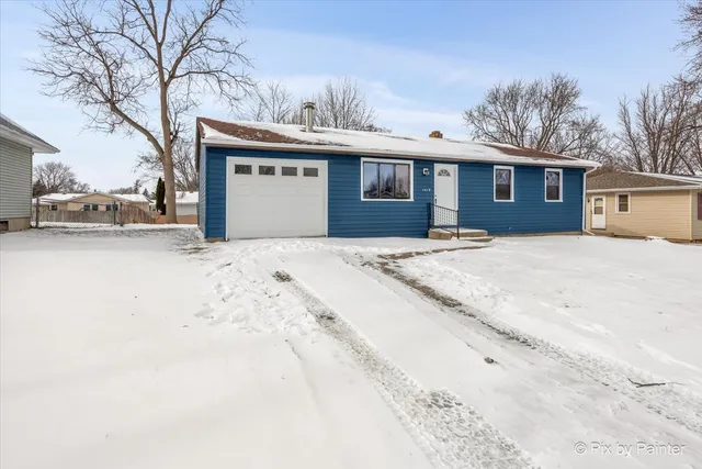 a front view of a house with a yard covered in snow